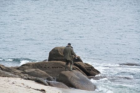 Man fishing on the rocks.の写真素材