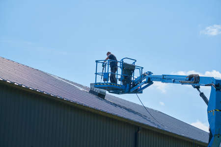 Man working on a roof from a basket.の写真素材