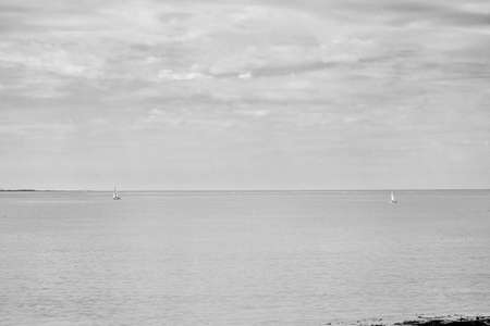Minimalist photo; two sailboats offshore.の写真素材
