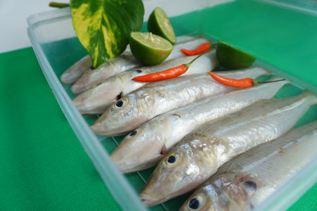 Sillago fish with lime and chilli on green background.