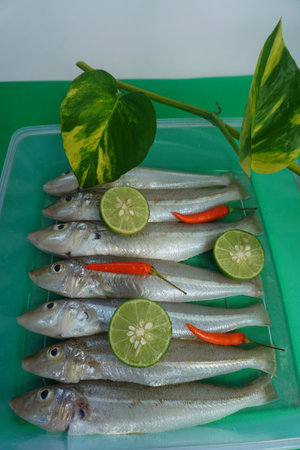 Sillago fish with lime and chilli on green background.