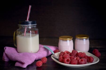 Yogurt breakfast with raspberries and milk on dark wooden background horizontal viewの写真素材