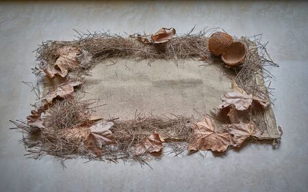 view of a rectangle made with bottom sackcloth on which are arranged in a frame, dry leaves and coconut shells in the upper left cornerの写真素材