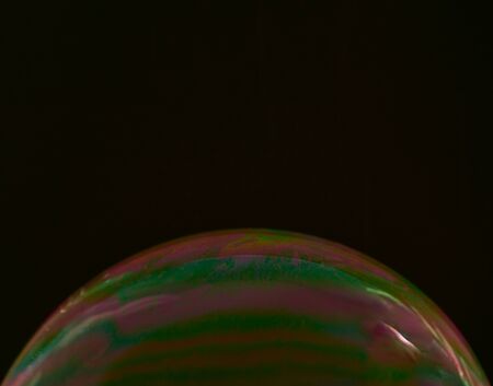half soap bubble on a black background, with multicoloured details on its surfaceの写真素材