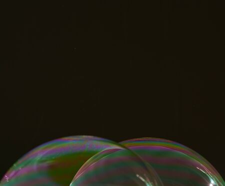 two half soap bubbles superimposed on a black background, with multicoloured details on the surfaceの写真素材