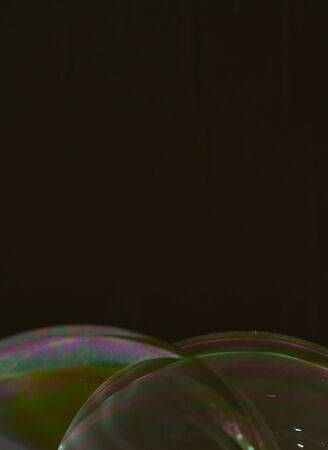 two half soap bubbles superimposed on a black background, with multicoloured details on the surface. Vertical formatの写真素材