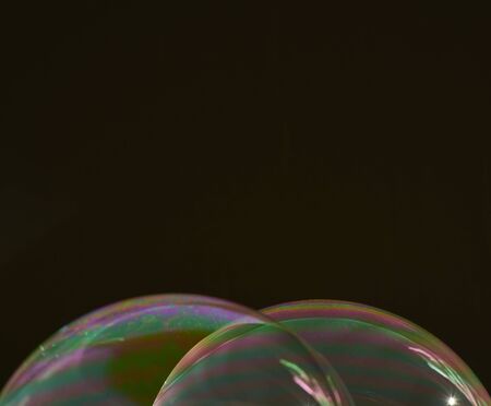 two half soap bubbles superimposed on a black background, with multicoloured details on the surface...