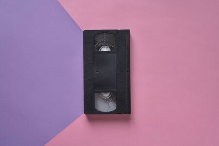 Top view of Large picture of an old Video Cassette tape on a pink and purple background . Minimalistic retro conceptの写真素材