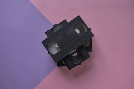 Pile of black vhs videotapes on a pink and purple background.Minimalistic retro conceptの写真素材