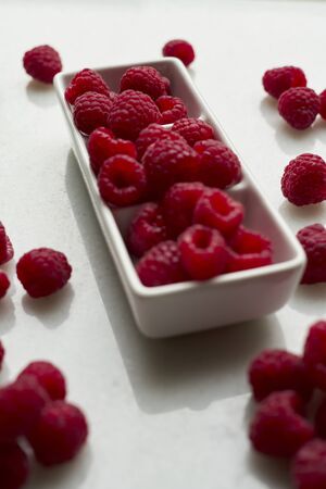 Closeup of raspberries in a white bowl on white background, Copy spaceの写真素材