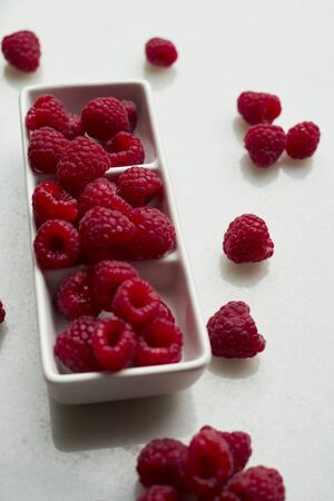 Closeup of raspberries in a white bowl on white background. Copy spaceの写真素材