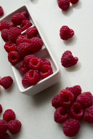Raspberries on a white background.Ceramic box with fresh raspberries. Copy spaceの写真素材