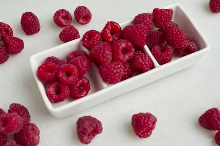 Closeup of raspberries in a white bowl on white background, Copy spaceの写真素材