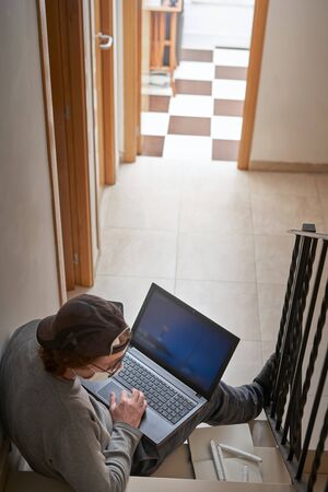 man working or learn from home with laptop and medicine health care mask on stair.Stay at homeの写真素材