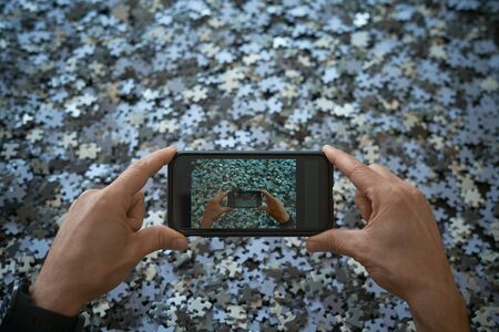 Person photographs with mobile phone a lot of puzzle pieces, stay at homeの写真素材
