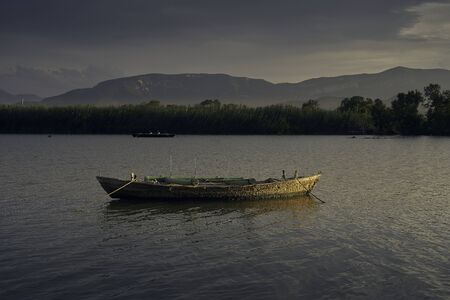 Sunset on one day cloudy in the famous lake of the albufera of Valencia, spain with a boat in the front.の写真素材