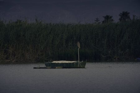 Sunset on one day cloudy in the famous lake of the albufera of Valencia, spain with a boat in the front.の写真素材