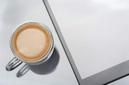 Close up of a cup of espresso with tablet computer on glassの写真素材