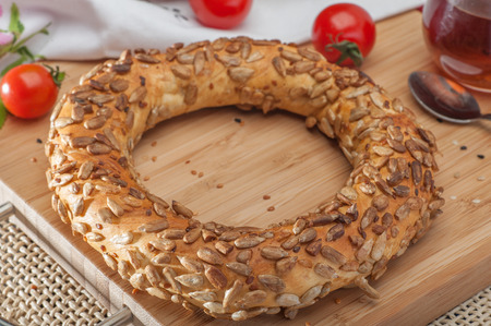 Close up of traditional Turkish bagel with sunflower seeds surrounded by tomatoes and tea