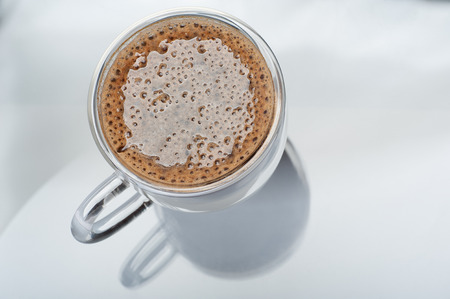 Close up of a cup of espresso in glass cup on glass table with reflectionの写真素材