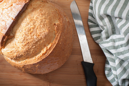 Close up of traditional Turkish round bread on cutting board with knife