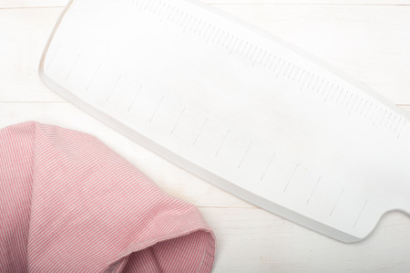 White cutting board on wooden background with a napkin