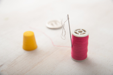 Macro shot of thread and needle on white wooden background