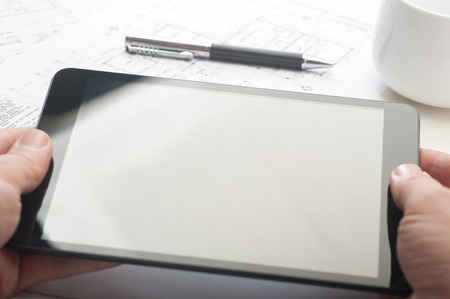 Businessman using a tablet device at the office, with blank screenの写真素材