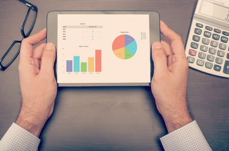 Businessman checking statistics on his tablet device, viewed from top