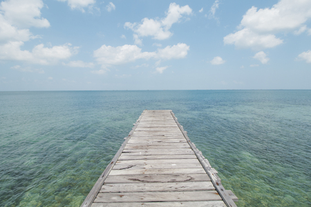 Wooden Dock, Clear Sea Water, Cloudy Sky and Tropical Beachの写真素材