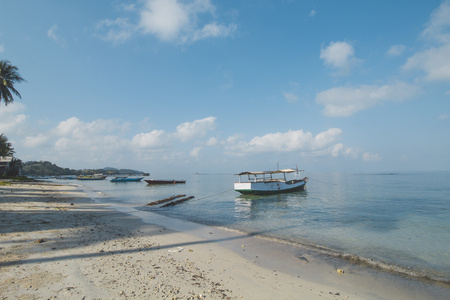 Clear Sea Water, White Sand, Cloudy Blue Sky, Wooden Boat and Tropical Beachの写真素材