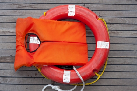 Orange life jacket. Old rescue vintage lifevest object for safe sailing isolated on wooden...