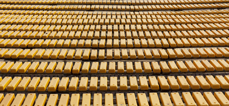 Row of yellow wooden seats on a spectator grandstand photo. Bench in the park for the show