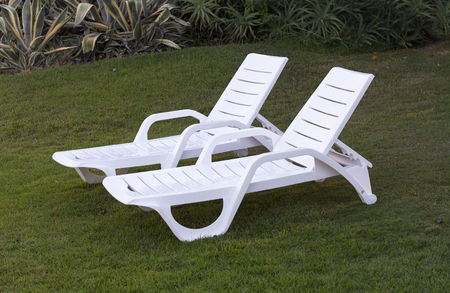 white lounge sunbeds standing on green grass in park photo