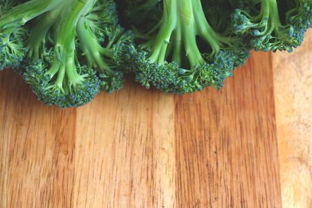 Close up of a plant of broccoli with a wooden chopping board on the background.の写真素材