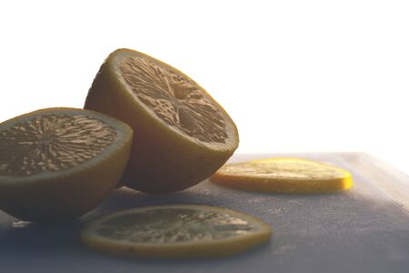 Close up of a sliced lemon on a cutting board against a white background