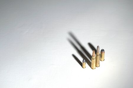 Crime family concept. Bullets on a white surface with long, dark,  dramatic shadows.