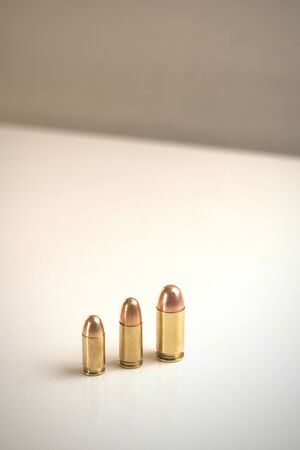 Three bullets of different calibers on a white surface. From left to right: .380 Auto FMJ9x19mm...