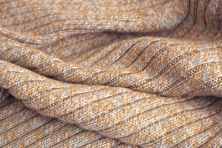 Mottled beige knitted woollen sweater. Texture detail close up.