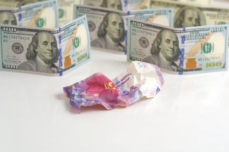 Argentina economic crisis, currency devaluation. Crumpled argentinian banknote and intact US banknotes. Concept metaphor.の写真素材