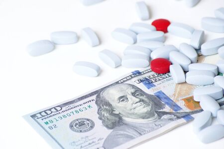 Health insurance, business concept. Red and blue pills on white background next to a hundred dollar billの写真素材