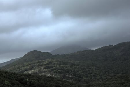 Overcast, heavy sky looming over dark mountains in Italy.の写真素材