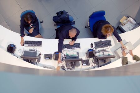 Three customer service agents working at a help desk at the airport.の写真素材