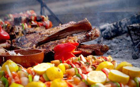 Traditional argentinian barbecue. Large piece of meat and vegetables skewers on the grill.の写真素材