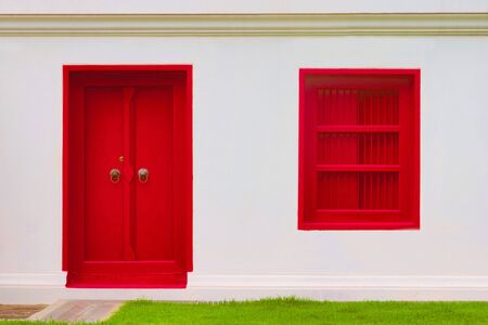 Intense blood red painted door and window on a white wall. Saturated, bold color, high contrast image.の写真素材