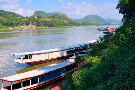 Long boats and barges sailing on the Mekong River near Luang Prabang, Laos.の写真素材