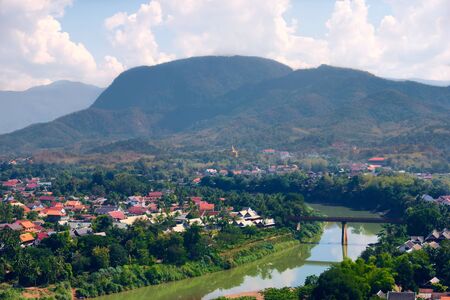 Elevated view of the town of Luang Prabang and Nam Khan river, in Laos. Lush jungle on the mountains can be seen on the background.の写真素材