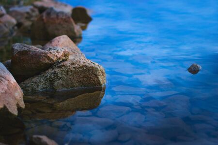 Natural stones on the shore of a lake at dusk. Tranquil scene, relaxing calm, zen meditation background.の写真素材