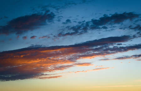 Twilight sky with dark sparse clouds receiving the last rays of sunlight.の写真素材