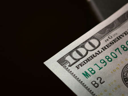 One hundred dollar bill. Focus on a corner, showing the number, with black negative space.の写真素材